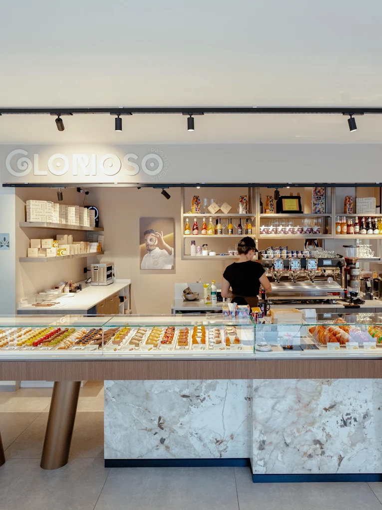 Il bancone della pasticceria Glorioso con la vetrina di monoporzioni e l'insegna sul fondo