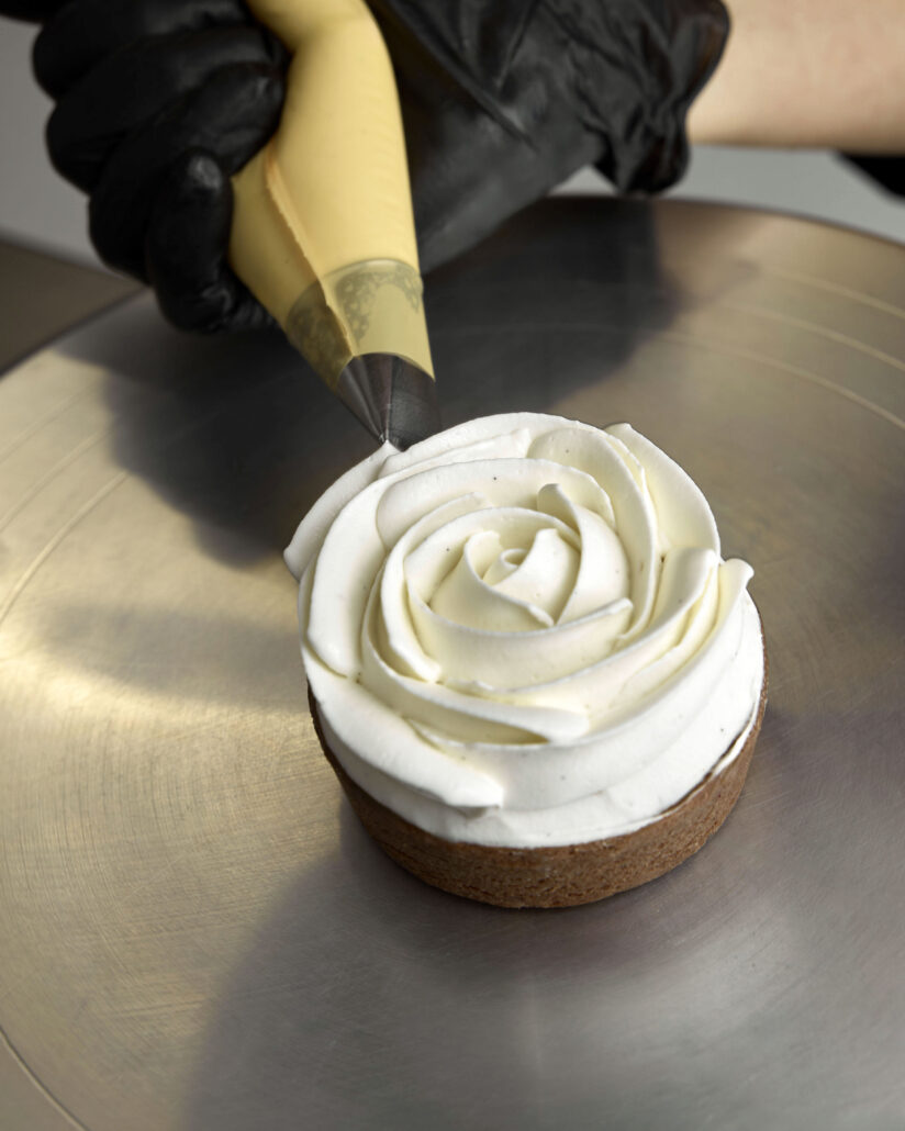 Decorazione a rosa di panna montata su una base di frolla
