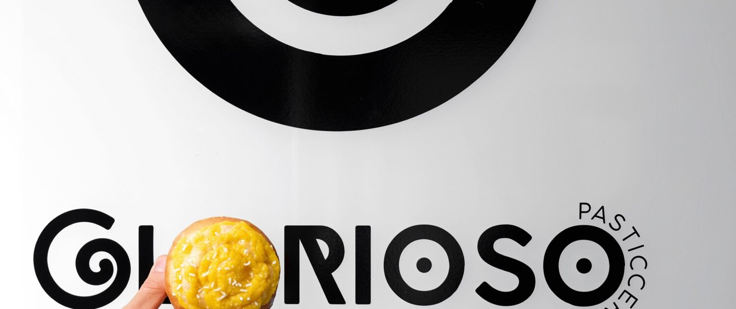 Una mano regge una brioche davanti al logo Glorioso