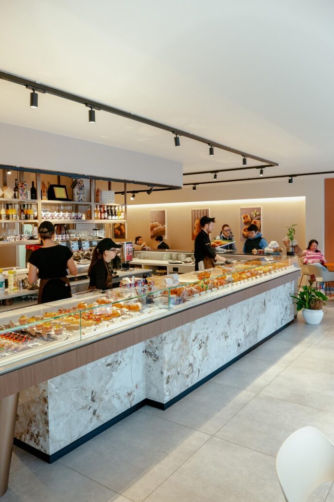 Il lungo bancone in marmo della pasticceria visto di lato, con la vetrina dei dolci