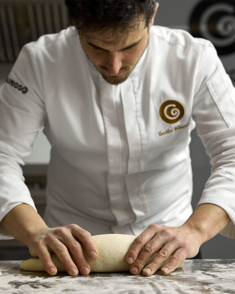 Il pasticcere lavora un impasto a mano sul bancone infarinato