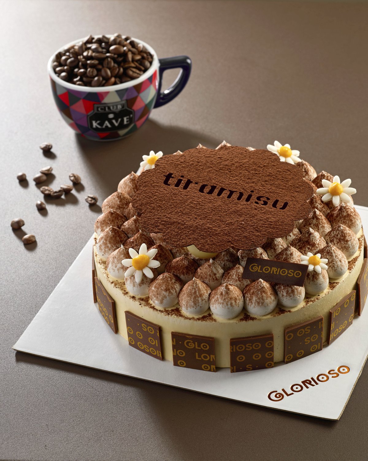 Torta tiramisù con margherite di zucchero, cacao in polvere e chicchi di caffè