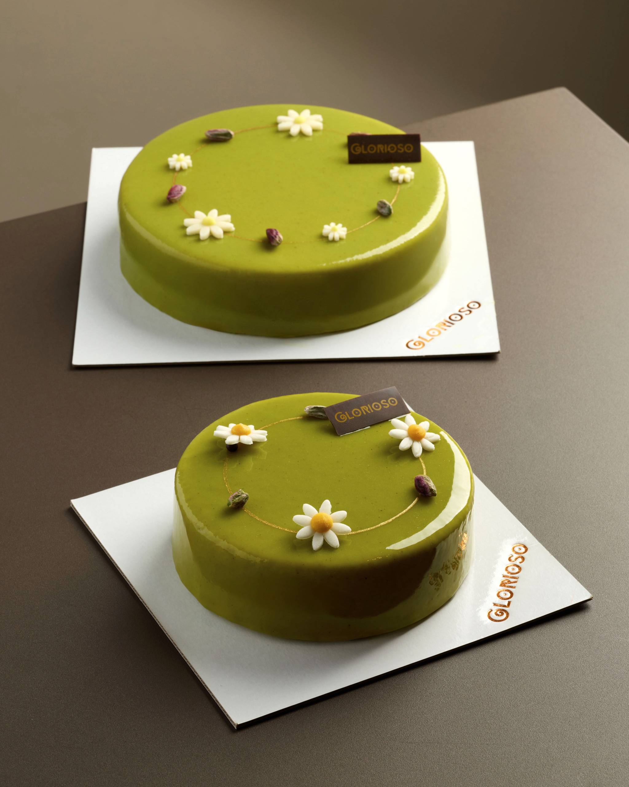 Torta verde con glassa a specchio al pistacchio, decorata con fiori di pasta di zucchero