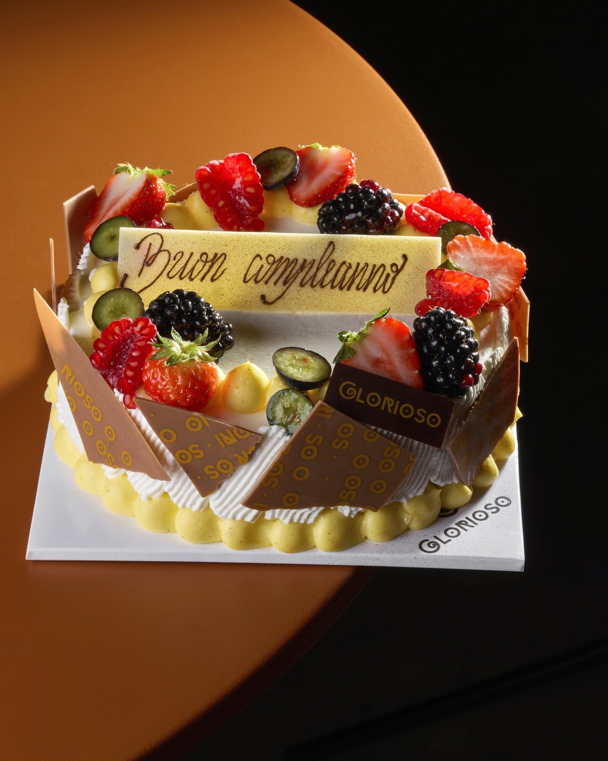 Torta di compleanno con frutti rossi freschi e targhetta al cioccolato bianco