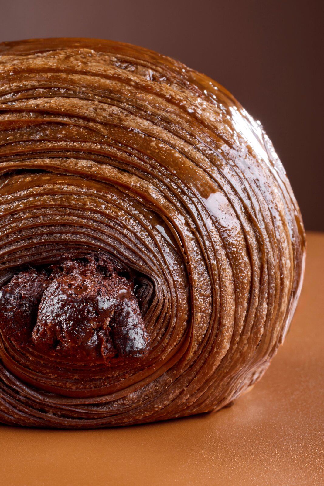 Dettaglio a spirale di un cornetto sfogliato con cuore di cioccolato e glassa di caramello