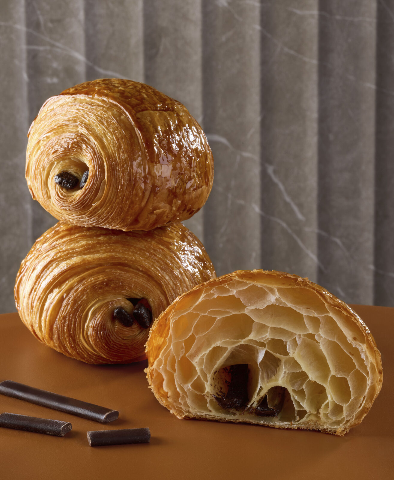 Due pain au chocolat sfogliati, uno tagliato a metà con il cioccolato in vista